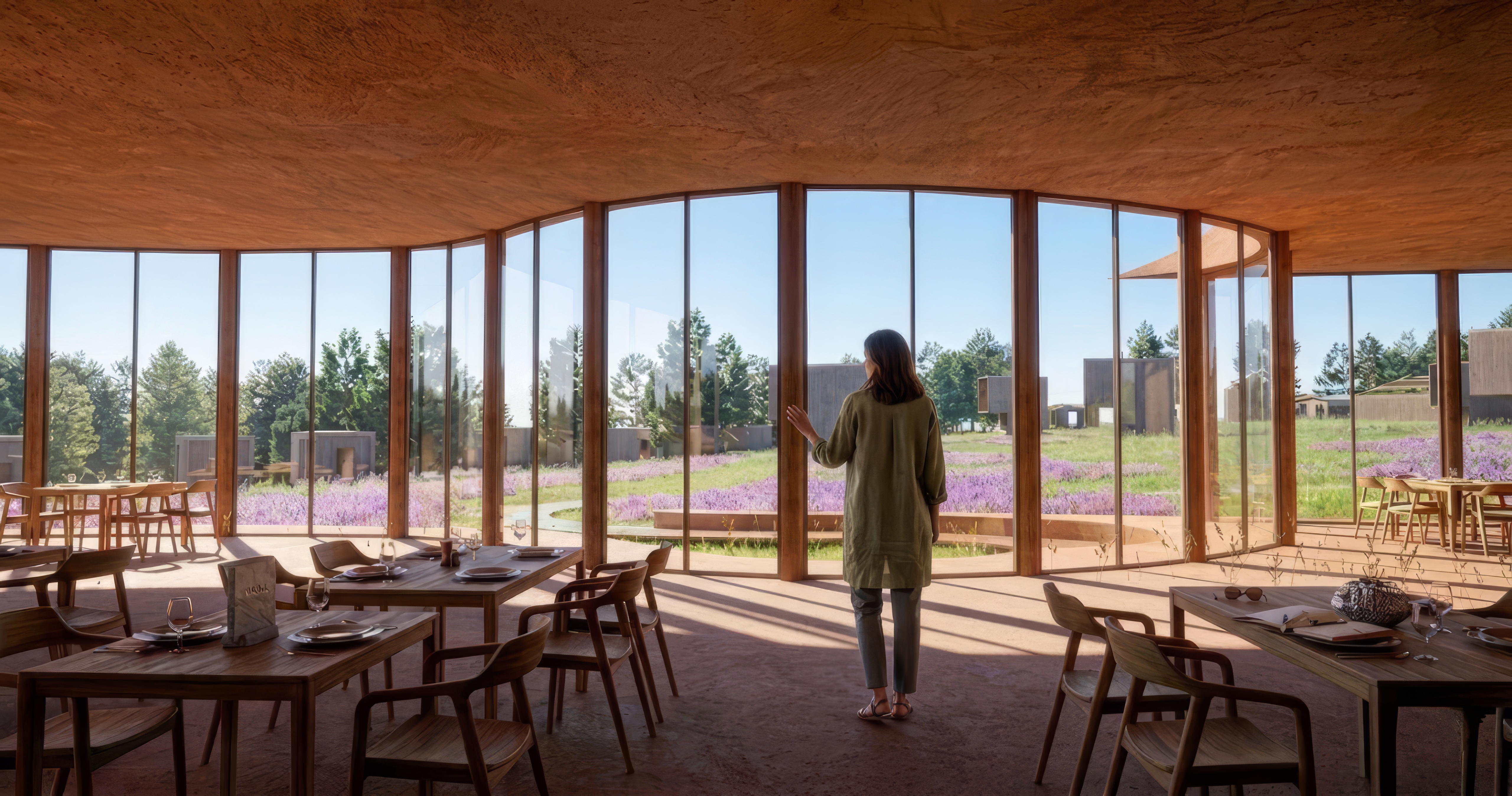 The main restaurant at Террасы with its curved glass facade: the window works as a moment opening onto the flower garden and the dispersed cabins beyond. The place is the source of energy, the architecture amplifies it.